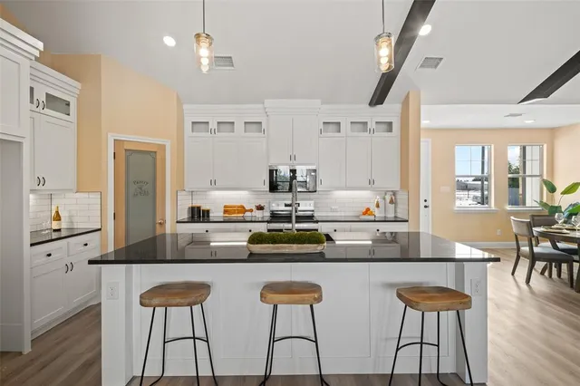 a kitchen with stainless steel appliances a dining table chairs and wooden floor