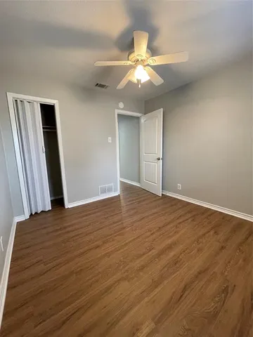 an empty room with wooden floor and chandelier fan