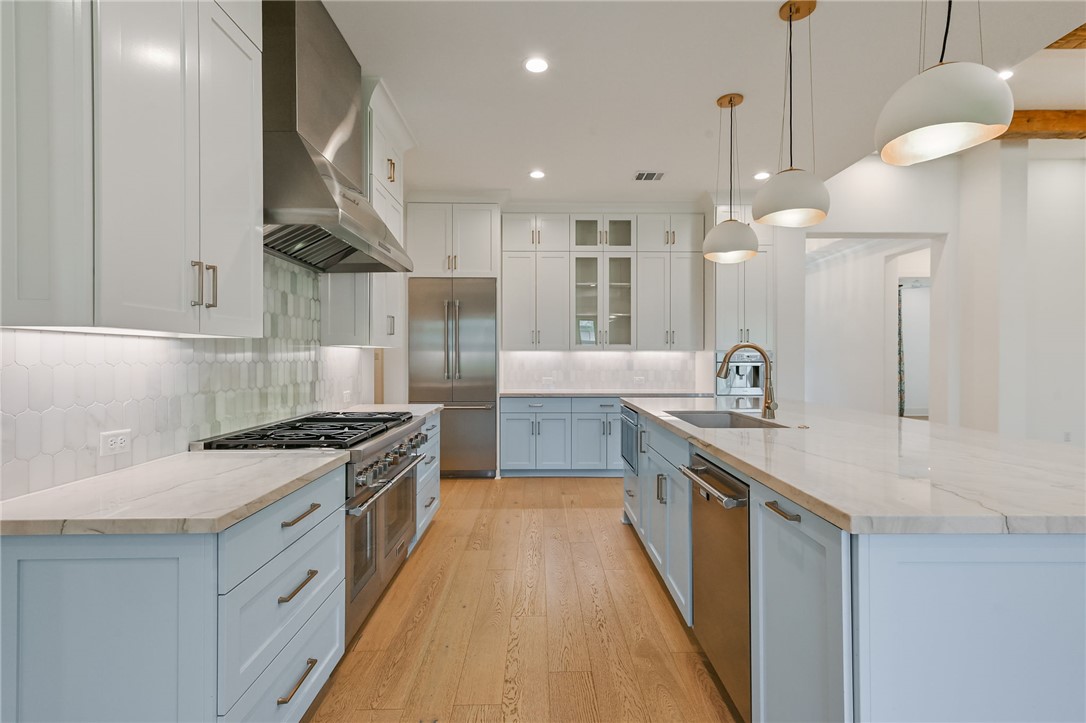 5115 Inverness Drive Bryan, TX 77802 - Photo 9 of 28 Kitchen featuring a large central island with a light blue finish, light wood-finish flooring, white upper cabinetry, light blue lower cabinetry, and stainless steel appliances