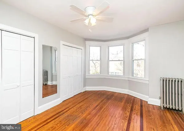 a view of empty room with wooden floor and fan