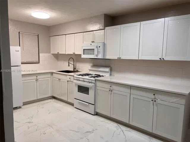 a kitchen with white cabinets and white appliances