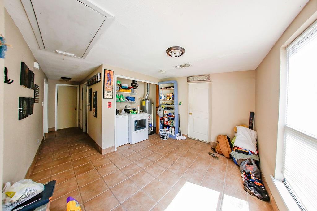 6730 Pine Mill Road Reno, TX 75462 - Photo 11 of 21 Rec room featuring attic access, washer and dryer, light tile patterned floors, and gas water heater