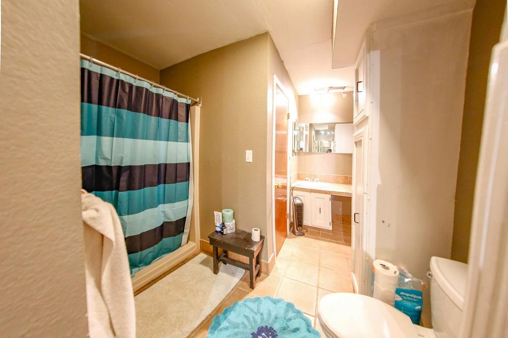 6730 Pine Mill Road Reno, TX 75462 - Photo 19 of 21 Bathroom with toilet, tile patterned flooring, curtained shower, and a sink