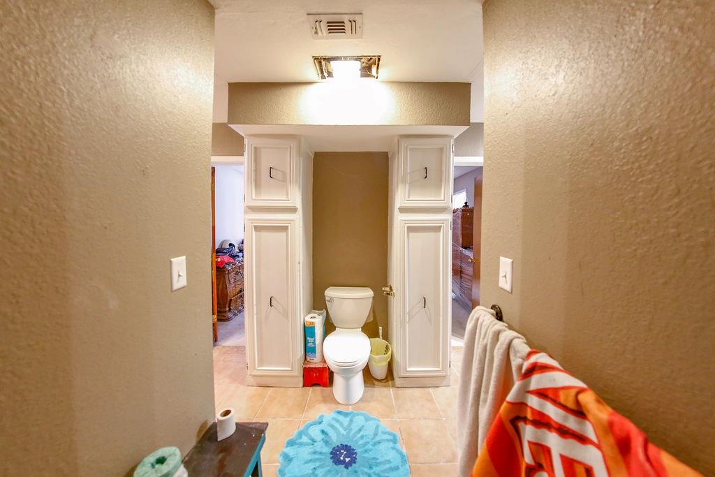 6730 Pine Mill Road Reno, TX 75462 - Photo 5 of 21 Bathroom featuring a textured wall, tile patterned floors, and toilet
