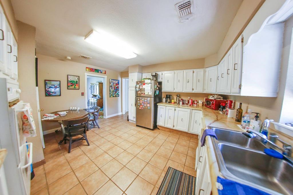 6730 Pine Mill Road Reno, TX 75462 - Photo 9 of 21 Kitchen featuring freestanding refrigerator, a sink, light tile patterned flooring, white cabinetry, and light countertops