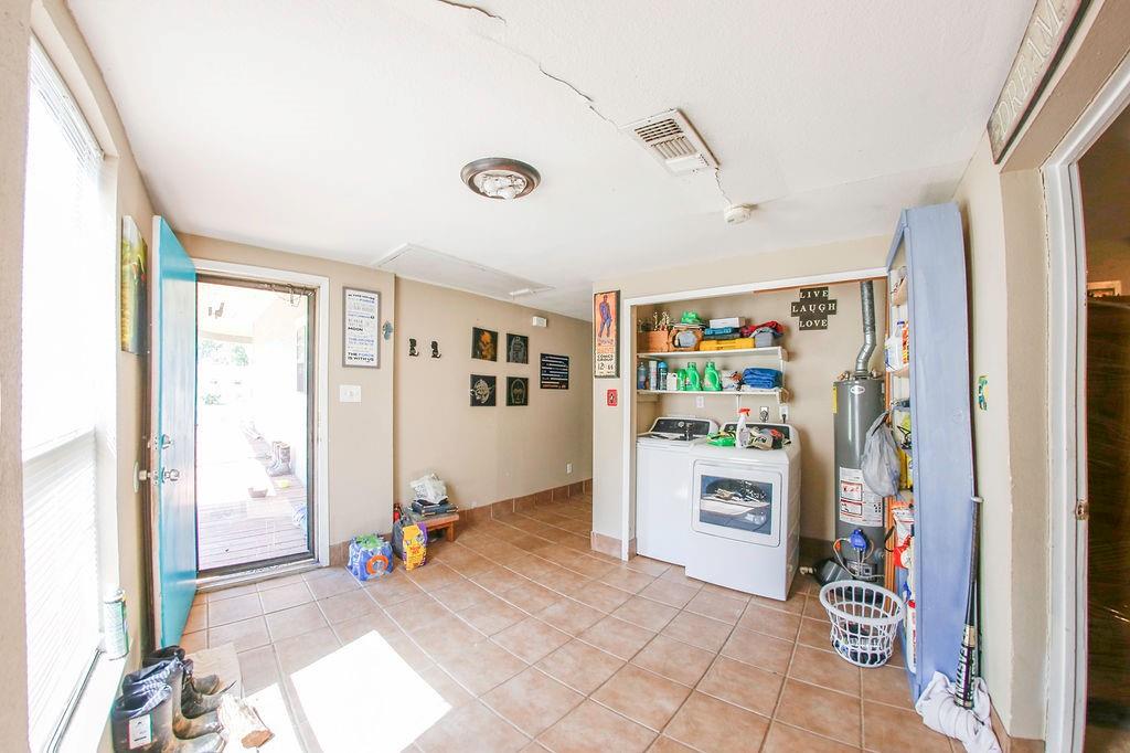 6730 Pine Mill Road Reno, TX 75462 - Photo 10 of 21 Kitchen with washing machine and dryer, light tile patterned floors, and water heater