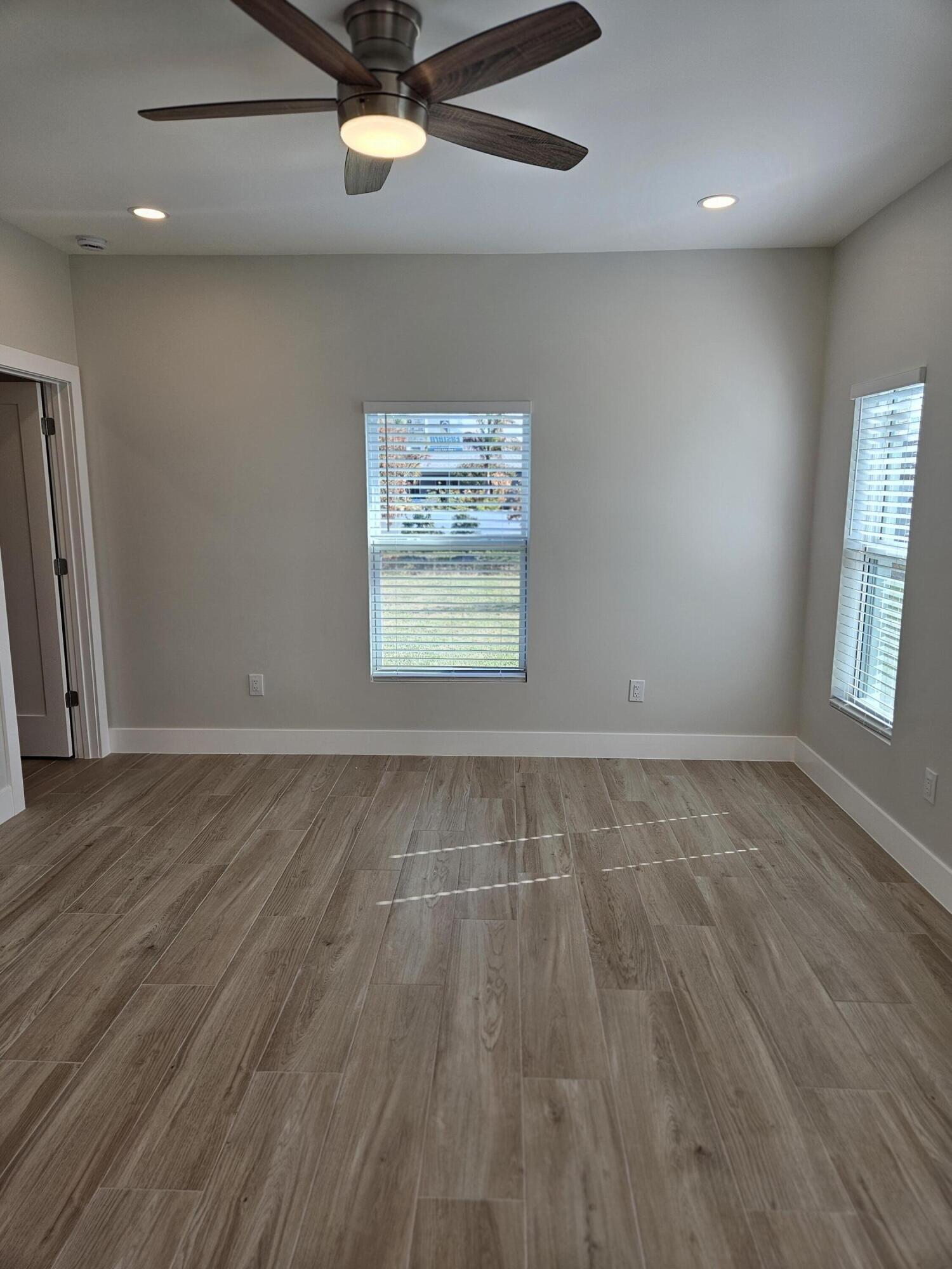 3838 Southeast Grant Street Stuart, FL 34997 - Photo 21 of 39 an empty room with wooden floor chandelier fan and windows