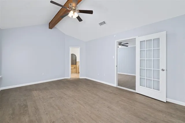 a view of empty room with wooden floor and ceiling fan