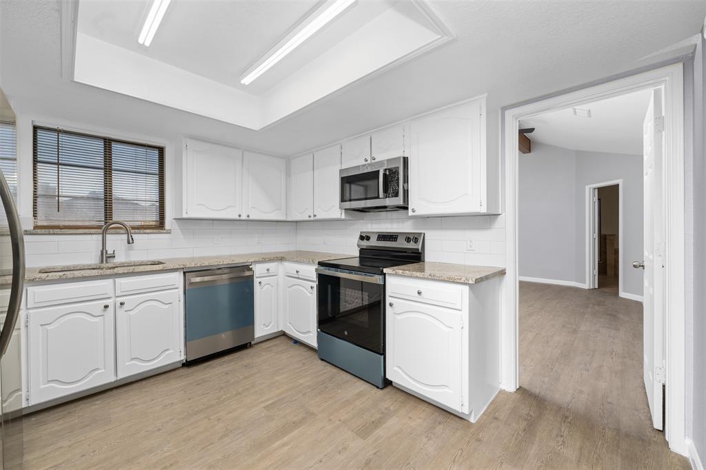 720 Sandy Trail Fort Worth, TX 76120 - Photo 8 of 24 a kitchen with granite countertop a sink stainless steel appliances and white cabinets