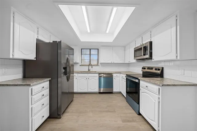 a kitchen with granite countertop white cabinets and stainless steel appliances