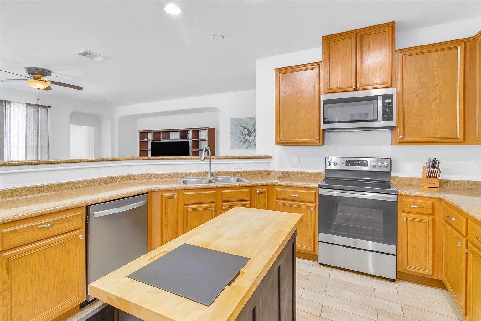 460 Waterleaf Boulevard Kyle, TX 78640 - Photo 11 of 30 A well-equipped kitchen features honey-toned cabinetry and stainless steel appliances, creating a functional cooking space.