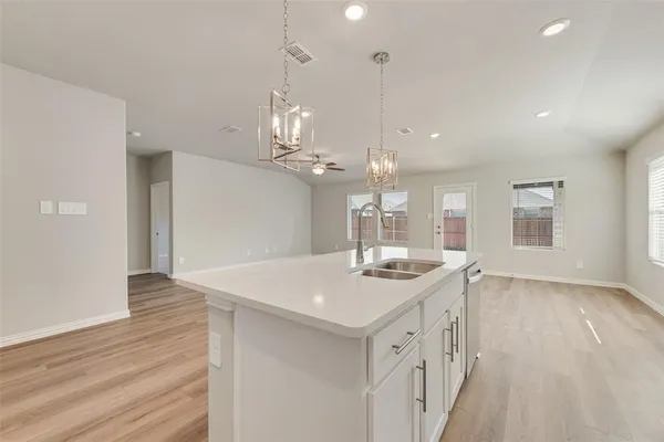 a kitchen with a sink chandelier and wooden floor