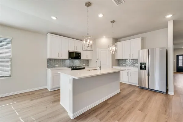 a kitchen with refrigerator a microwave and white cabinets