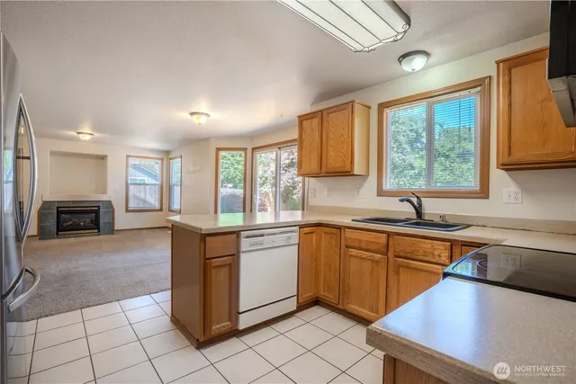 a kitchen with stainless steel appliances granite countertop a stove top oven a sink dishwasher a dining table and chairs with wooden floor