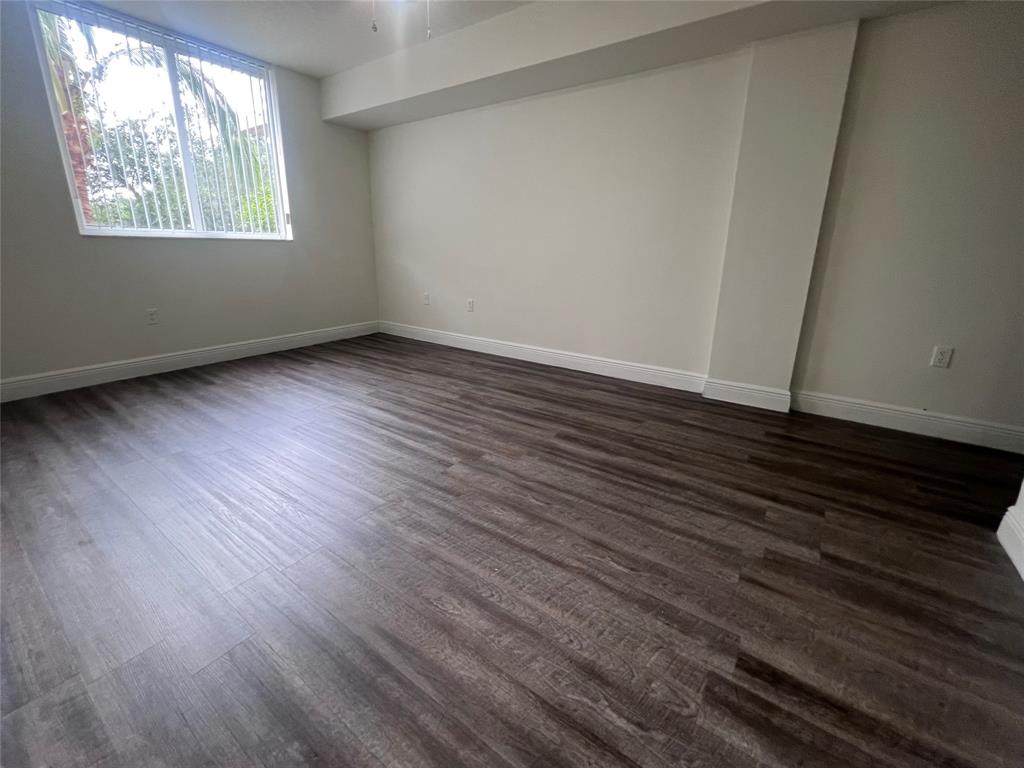 18335 Northwest 68th Avenue, Unit 255308 Hialeah, FL 33015 - Photo 8 of 17 a view of an empty room with wooden floor and a window