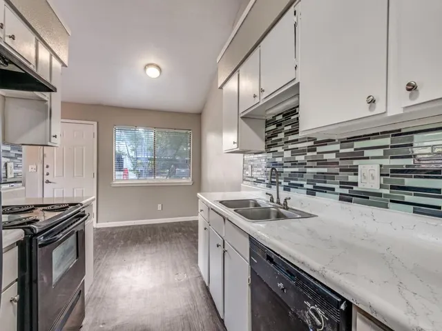a kitchen with granite countertop a sink stove and cabinets