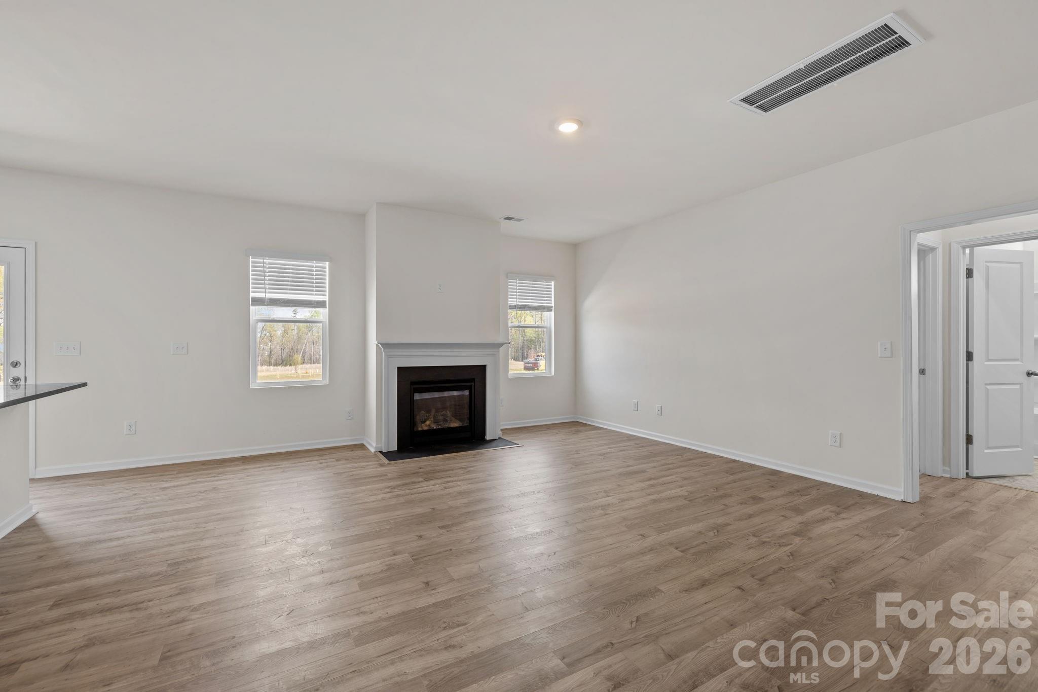 463 Brick House Road York, SC 29745 - Photo 14 of 35 an empty room with wooden floor fireplace and windows