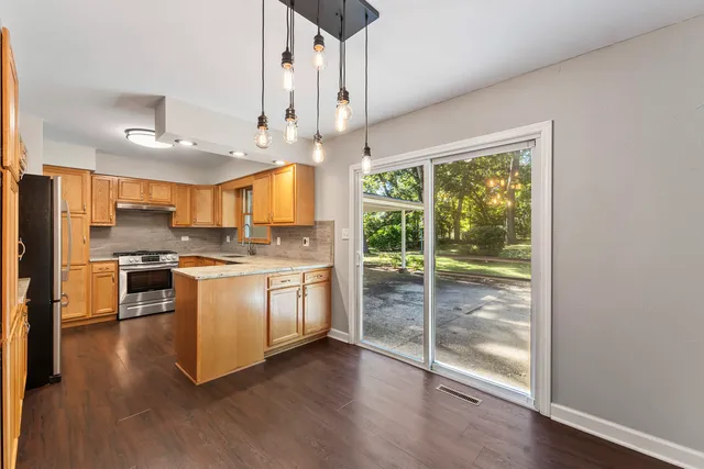 a kitchen with stainless steel appliances granite countertop a refrigerator a stove a sink and a large window