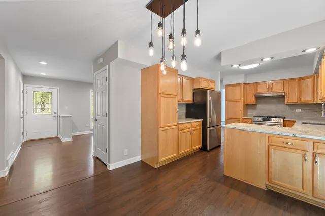 a kitchen with stainless steel appliances kitchen island wooden floors and white cabinets