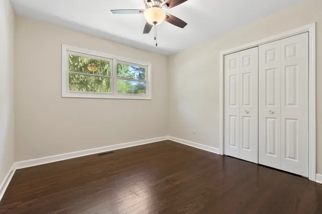 a view of an empty room with wooden floor and window