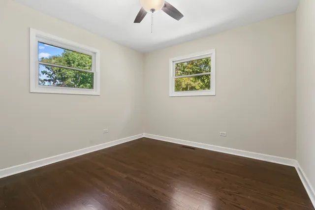 a view of an empty room with wooden floor and window