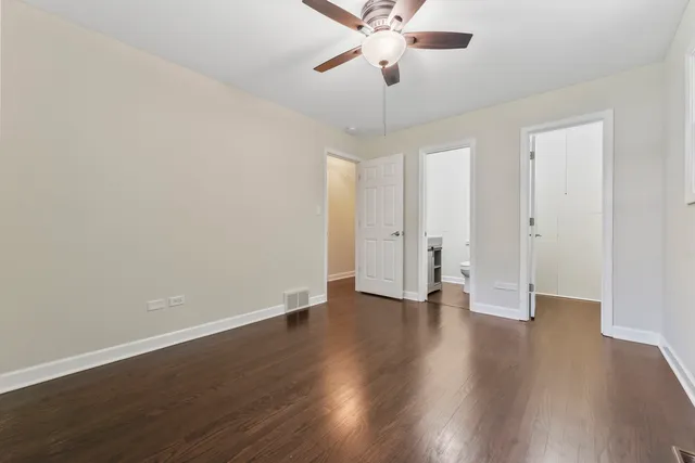 an empty room with wooden floor and ceiling fan