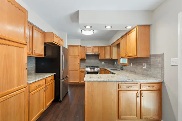 a kitchen with a refrigerator a sink and wooden cabinets