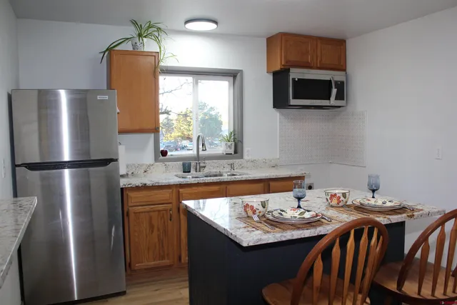 a kitchen with stainless steel appliances granite countertop a sink a microwave refrigerator and a window