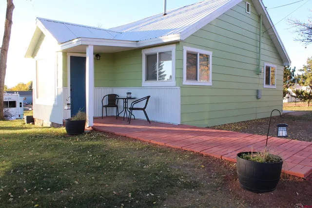 a view of a backyard with table and chairs and a barbeque