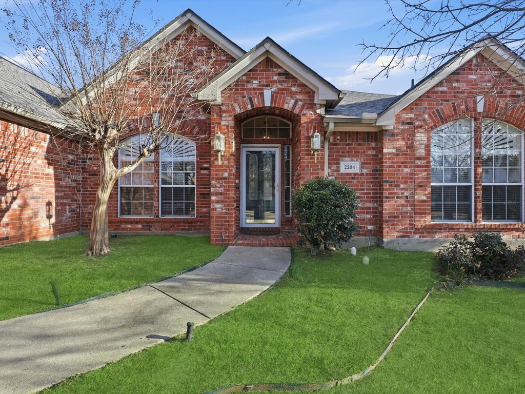 2204 Woods Edge Court Corinth, TX 76210 - Photo 1 of 1 a view of a brick house with a large windows and a yard with plants and large trees