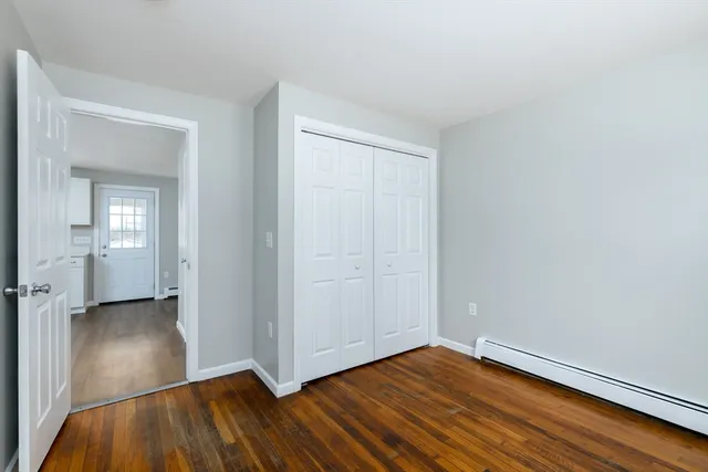 an empty room with wooden floor closet and windows