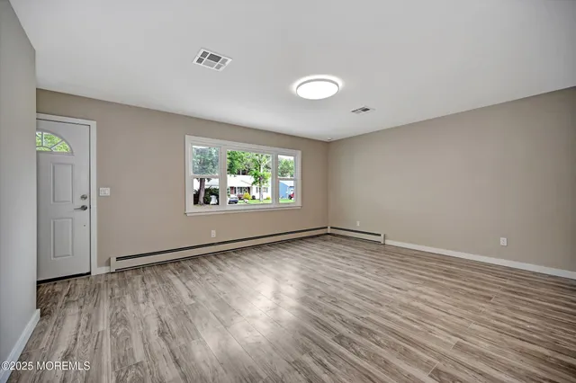 an empty room with wooden floor and windows