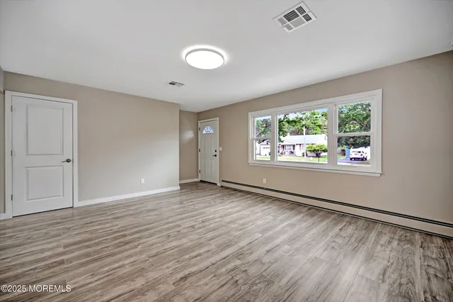 an empty room with wooden floor and windows