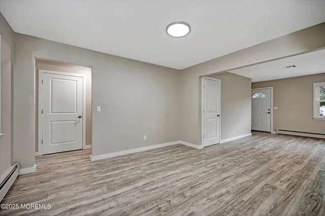 a view of an empty room with wooden floor and closet