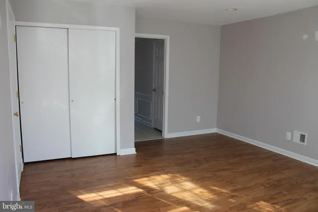 a view of an empty room with wooden floor and closet