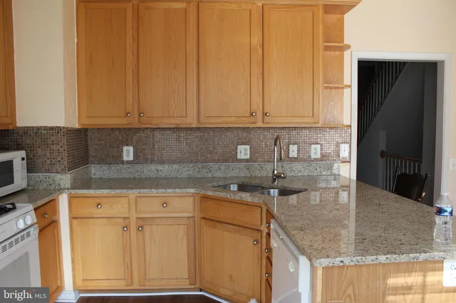 a kitchen with granite countertop a sink a stove and cabinets