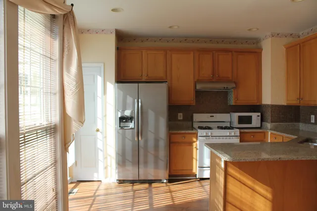 a kitchen with stainless steel appliances granite countertop a refrigerator a sink and a stove