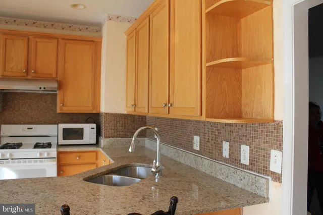 a kitchen with stainless steel appliances granite countertop a sink and a stove next to a window