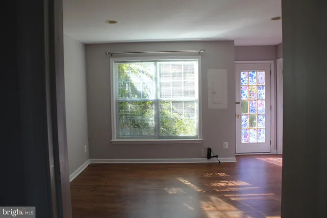 an empty room with wooden floor and windows