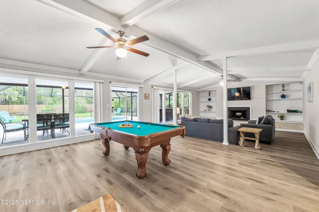 a room with furniture pool table wooden floor and windows