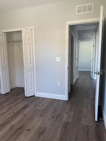 an empty room with wooden floor and closet area