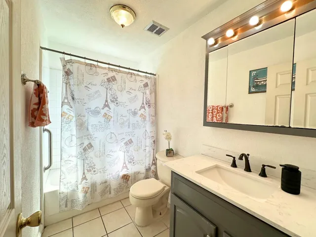 a bathroom with a granite countertop sink toilet a mirror a vanity and shower