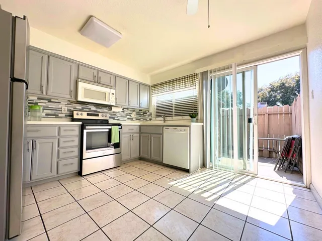 a kitchen with stainless steel appliances granite countertop a stove top oven a sink dishwasher and white cabinets with wooden floor