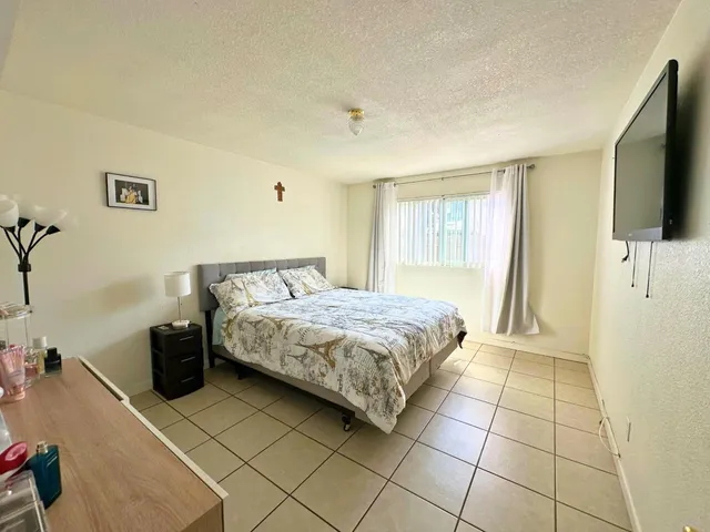 a spacious bedroom with a bed and a flat screen tv