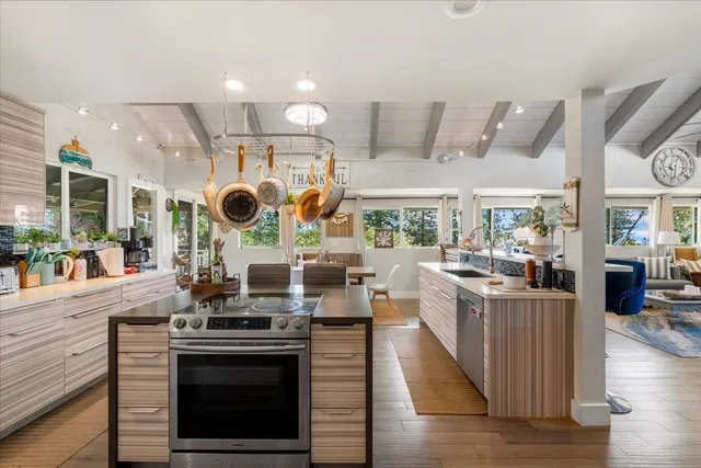 a kitchen with stainless steel appliances granite countertop a stove and a view of living room