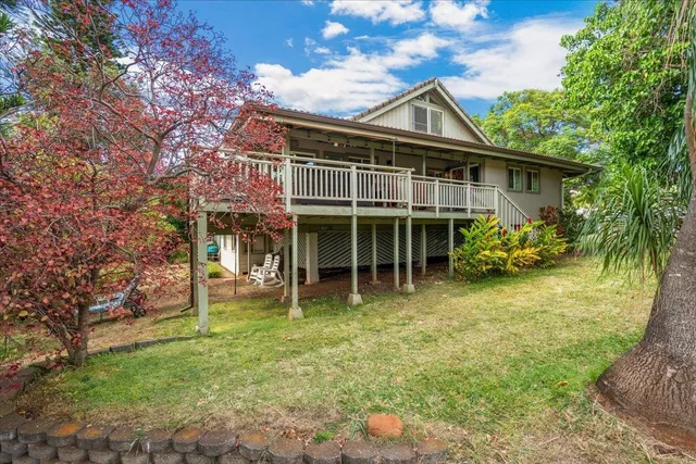 a view of house with a big yard and large trees
