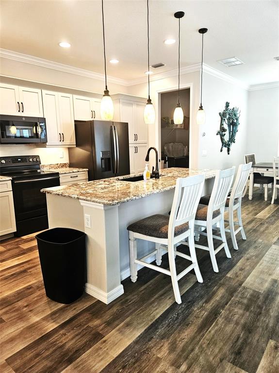 460 Marlin Road Venice, FL 34293 - Photo 14 of 44 a kitchen with stainless steel appliances a stove a refrigerator a sink a dining table and chairs with wooden floor