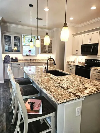 a large kitchen with stainless steel appliances kitchen island granite countertop a sink a stove and a wooden floors