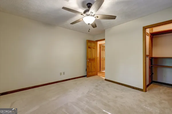 an empty room with closet and a ceiling fan