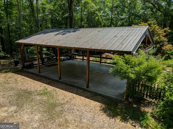 a view of a patio with a table and chairs under an umbrella with large trees